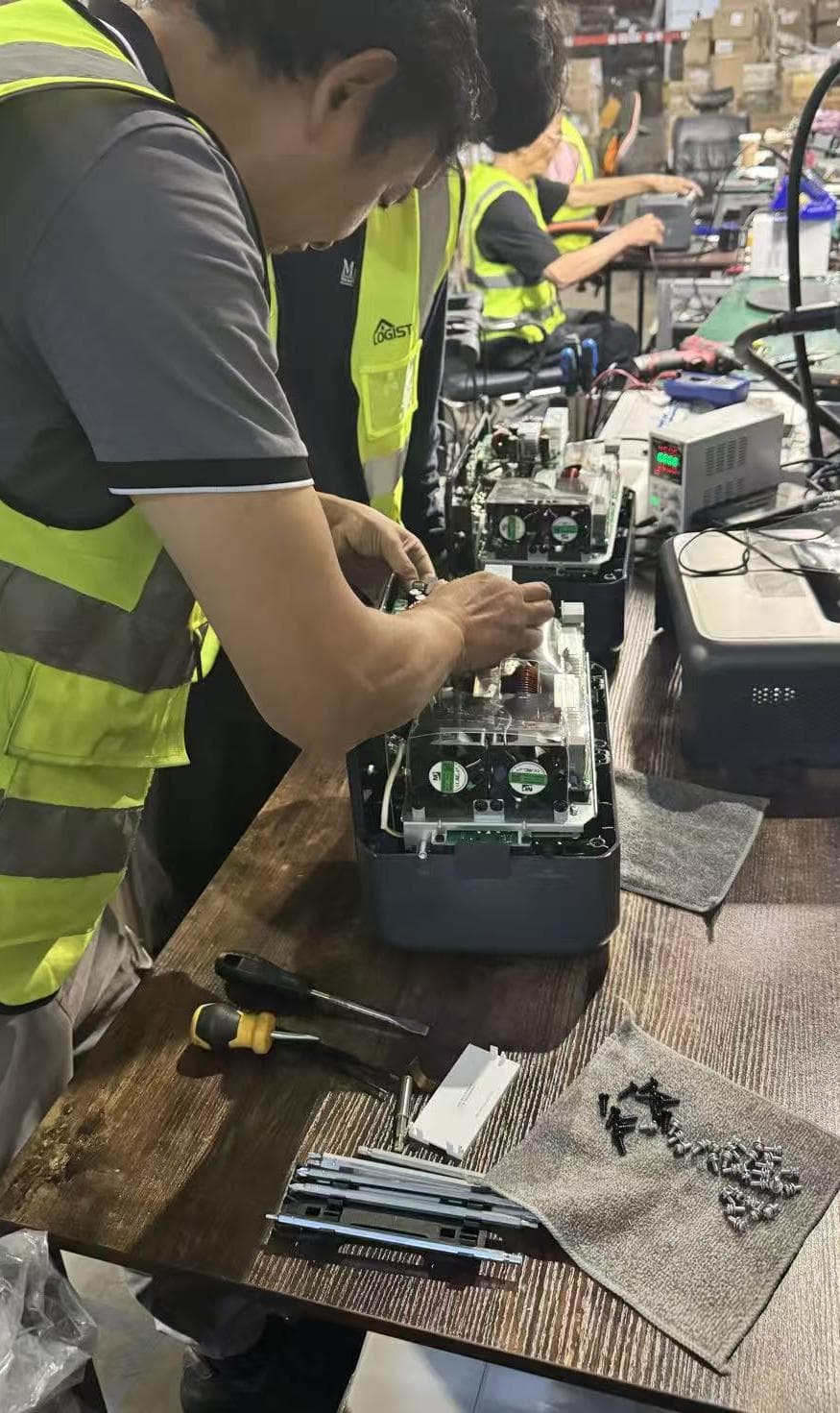Technicians in Logistar vests opening returned portable power stations at the repair bench