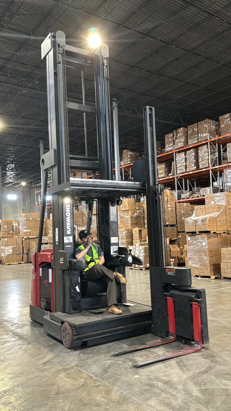 A turret truck operator between pallet racks on the warehouse floor