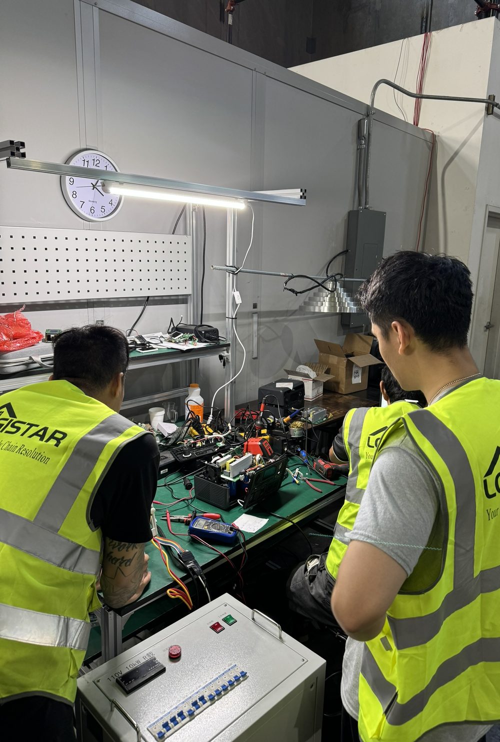 Technicians in hi-vis vests repairing a returned power station at the bench